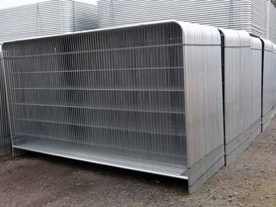 Many round top welded temporary fence panels are standing on the ground. They are bound together.
