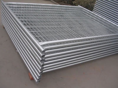 Many welded temporary fencing panels with round frame and square top lying on the floor neatly.
