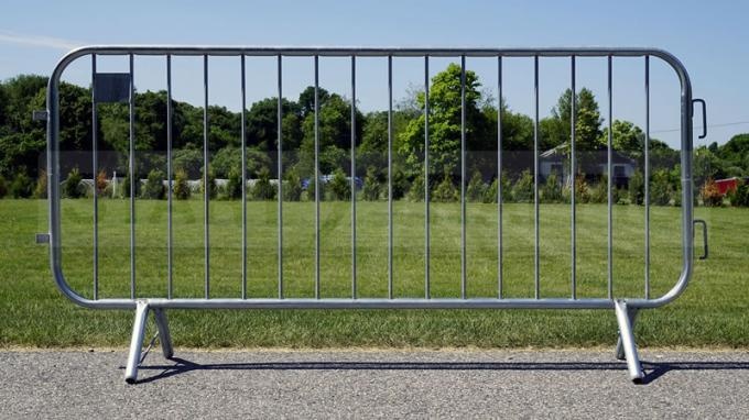 A barricade fence panel with crossed feet stands on the concrete.